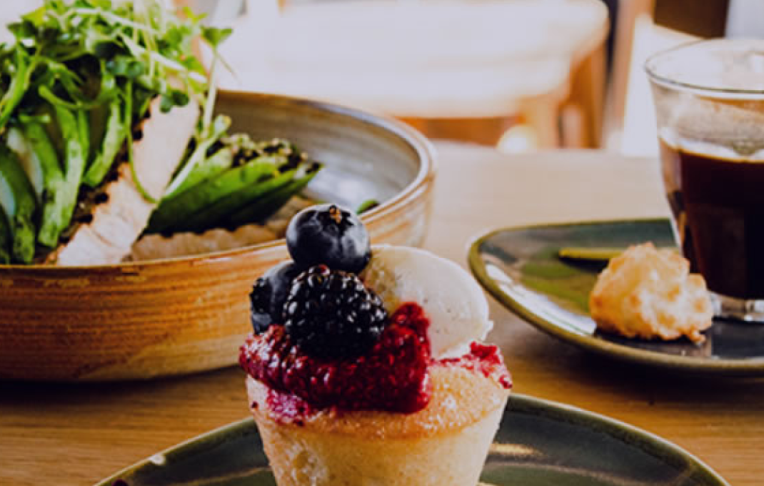 Various food items including cupcakes, pastries, and salads on wooden table